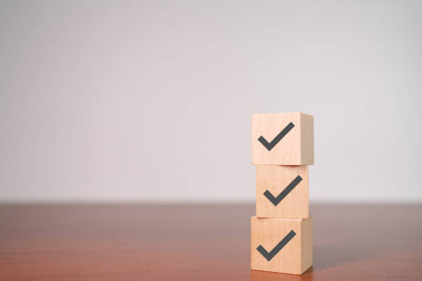 istock Check mark icons on wooden stacked blocks. Task lists, Checklist, Survey, Assessment, List, Confirm items, Double check, Quality Control. Goals achievement business success. 1805547497