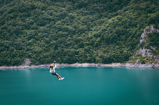 Young woman ziplining over Piva Lake in Montenegro