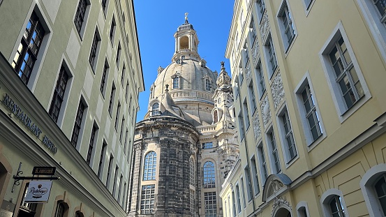 Dresden, Germany – September 2, 2023: The dome of the Church of Our Lady, or Frauenkirche in a traditional street of Dresden, Germany.