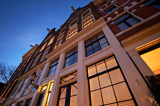 Canal house building facade with Illuminated windows at night in Amsterdam, The Netherlands.