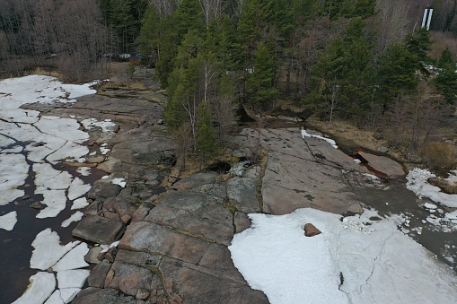 Snow covered rocks. Aerial view of a rocky lake shore covered with snow. A plot of forest near water in winter.