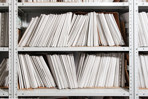 shelves with paper documents. Organized office space with neatly arranged paper documents and file cabinets.