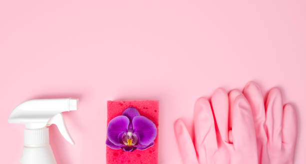 istock Spring cleaning concept. Detergent, orchid flower, kitchen sponge and rubber gloves on a pink background. Flatlay. Banner. Copy space. Top view. 1805607215