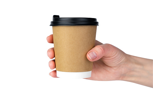 Woman's hand holds a craft disposable paper cup with fresh coffee isolated on a white background. Close-up.