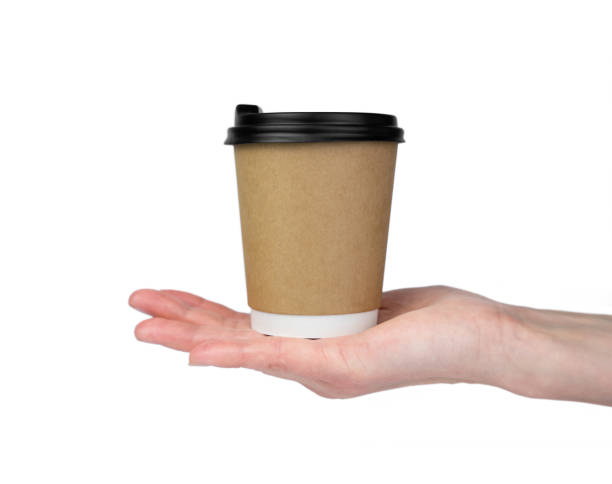 istock A woman's hand holds a disposable paper cup with coffee isolated on a white background. Coffee to go. Close-up. Selective focus. 1805609379