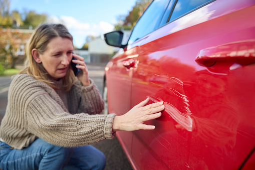 Unhappy Mature Female Driver With Damaged Car After Accident Calling Insurance Company On Mobile Phone
