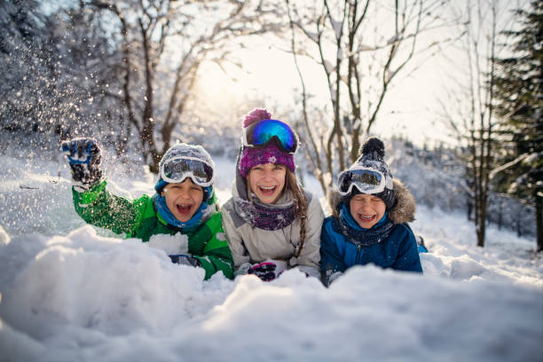 istock Three cute kids playing in snow on a sunny winter day 1805616895