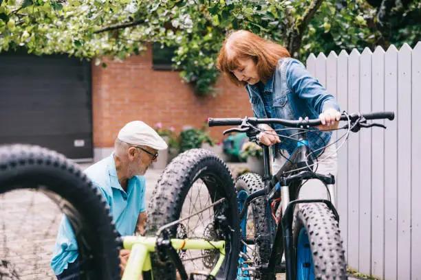 Senior couple, lovingly tends to the maintenance of their fatbikes, poised for a memorable journey together into the great outdoors.