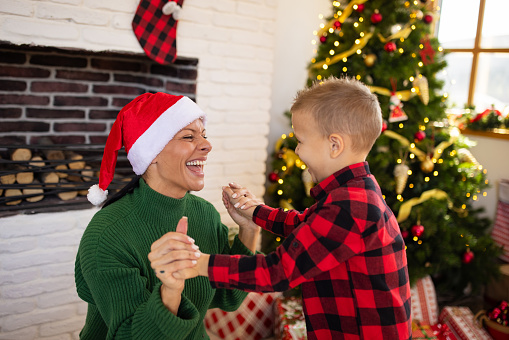 A mid adult Caucasian woman enjoying Christmas with her son in the living room of their apartment
