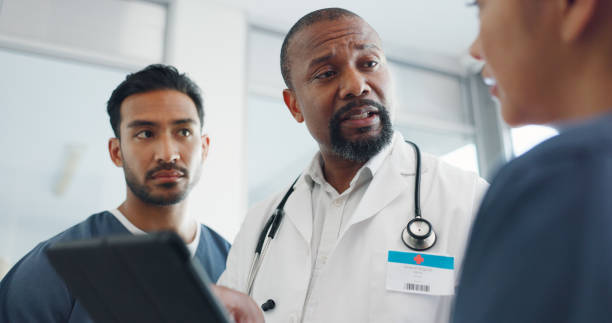 istock Tablet, doctors and team collaboration, discussion and hospital communication, conversation and doing medical research. Healthcare consultation, group nurses and surgeon teamwork on clinic cardiology 1805634533