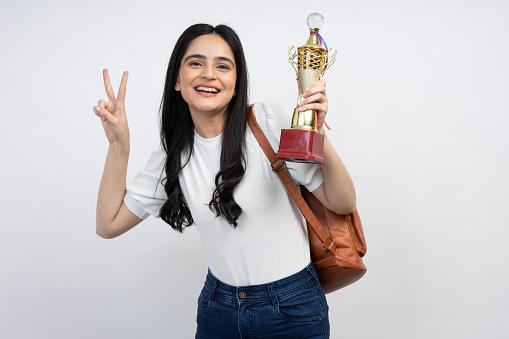 Happy modern student woman with bag showing trophy