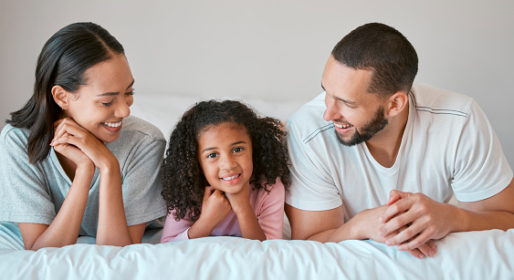 Family, portrait and home with a parents relax and resting with their little girl in the family home. Mother, father and daughter for caring, loving and bond relationship in the bedroom