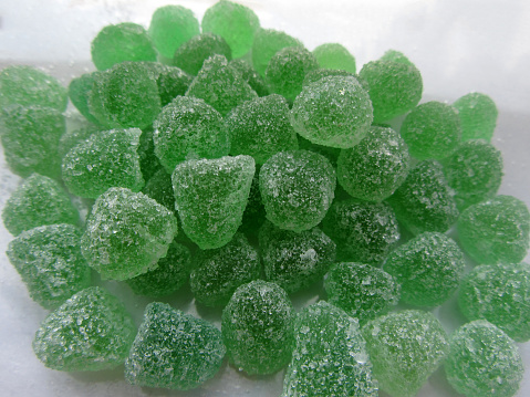 Close up photo of green jelly bean mint candies sprinkled with sugar.