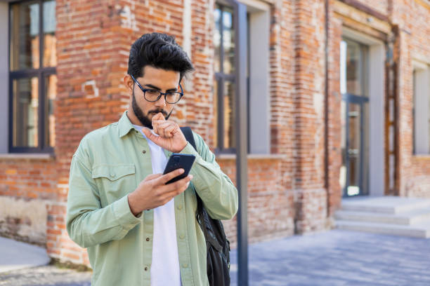 istock Upset and disappointed student with backpack outside university campus holding phone, reading bad news, man browsing social media, unhappy 1805645264