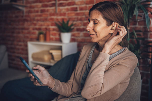 istock Woman using hearing aid in the ear while relaxing at home 1805647549