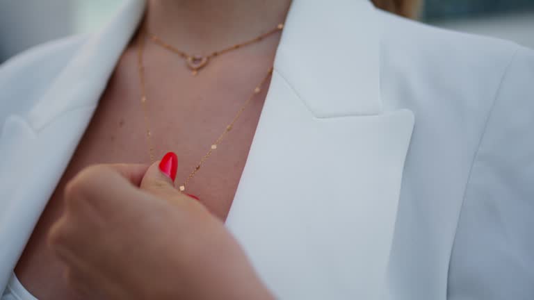 Woman hand touching jewelry on neck close up. Female fingers playing pendant.