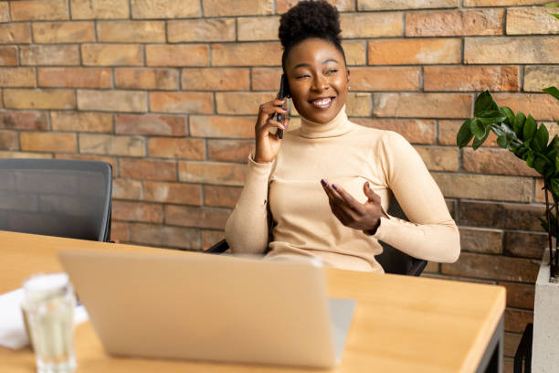 istock One young African American business woman using mobile phone while sitting by the brick wall in the industrial style office 1805654954