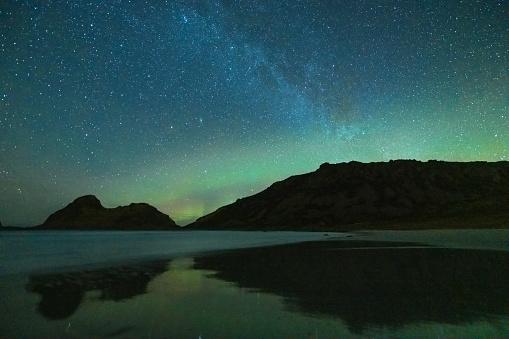 Starry night over Nykvag beach with faint Northern Lights, Aurora Borealis in Northern Norway during a cold winter night