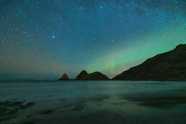 Starry night over Nykvag beach with faint Northern Lights, Aurora Borealis in Northern Norway stock photo
