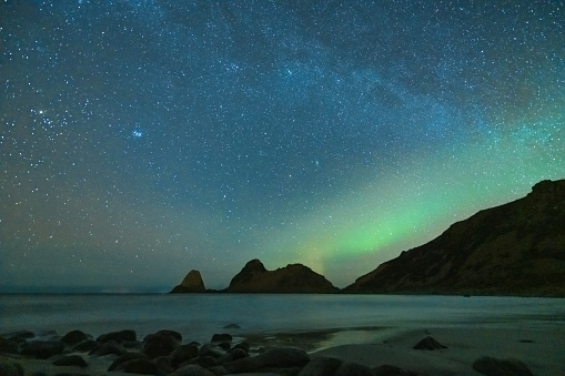 Starry night over Nykvag beach with faint Northern Lights, Aurora Borealis in Northern Norway during a cold winter night