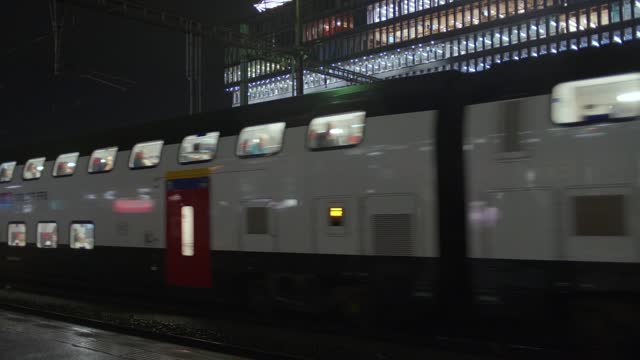 Train  with passenger cars departing from or arriving at main station in a European city at night, real time, no people