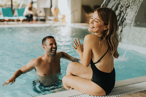 Handsome young couple having fun in the indoor swimming pool