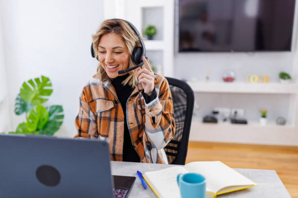 istock Young female operator wearing a headset and talking to a client, while sitting at home and working on her laptop 1805668341