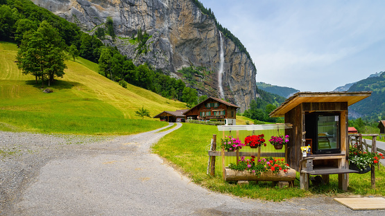 Lauterbrunnen, Switzerland - June 20, 2023: Traditional local houses in Lauterbrunnen valley in the Interlaken district in the Bern canton of Switzerland. Famous stunning touristic town with high cliffs. Bernese Oberland, UNESCO World Heritage Site