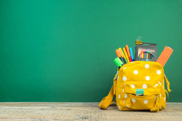 istock Backpack with different colorful stationery on table. Green background. Back to school. 1805682283