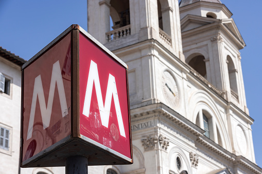 metro sign in front of the Church of Santissima Trinità dei Monti,  a Roman Catholic church in Rome. The church is best known for its position above the Spanish Steps which lead to the famous Piazza di Spagna; Rome, Italy
