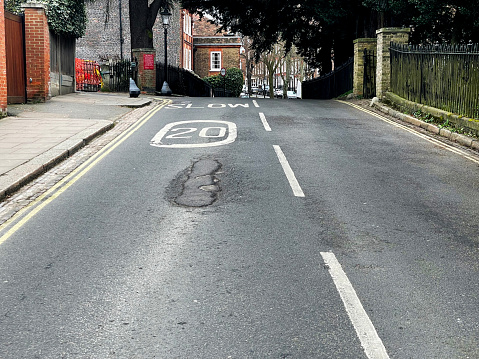 20 mph zone and slow road marking on a damaged road in Hampstead,  London. February 2023