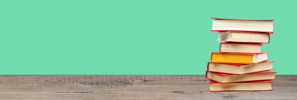 istock Composition with hardback books on wooden deck table and green background. Books stacking. Back to school. Copy Space. Education background. panorama, banner. Banner. 1805699169