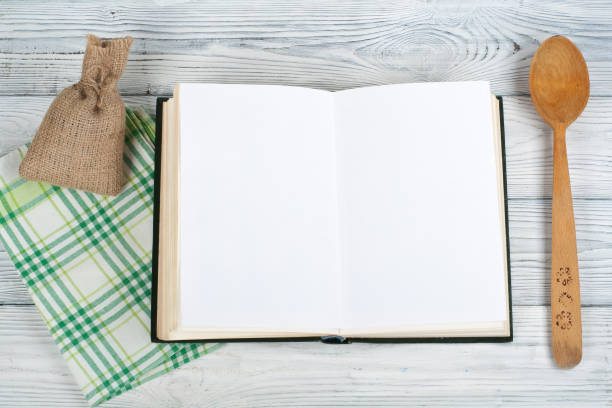 istock Recipe cook blank book on wooden background, spoon, rolling pin, checkered tablecloth. Top view 1805699175