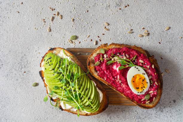 istock Whole grain toast with cream cheese, avocado, beetroot hummus, seeds, egg and microgreens (sprouted pea sprouts) on a light gray background. Healthy food concept. 1805703615
