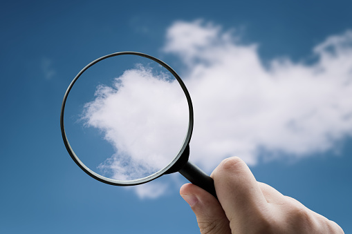 A magnifying glass focusing on a cloud on a blue sky