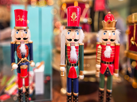 Soldier nutcracker statues standing in front of decorated Christmas tree with bokeh lights.