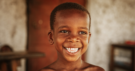 Close up portrait of a Cute Little African Kid with a Big Beautiful Smile Looking at the Camera. Happy Male Child in a Rural Area Representing Innocence, Peace and Hope. Documentary Footage