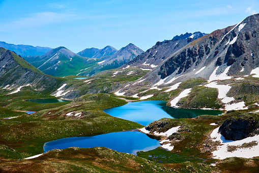 A breathtaking summer vista in the Swiss Alps unveils lush green mountains and picturesque valleys, harmonizing nature's beauty in a captivating alpine landscape.