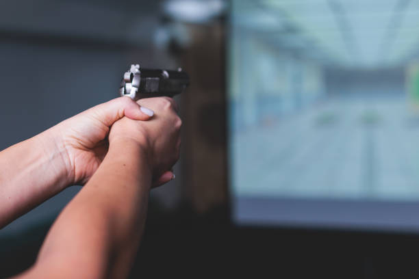 istock Process of shooting target at the shooting rifle range, women practicing with hand gun pistol at shooting gallery, firearms training, pointing weapon on digital screen, live fire digital targeting 1805737735