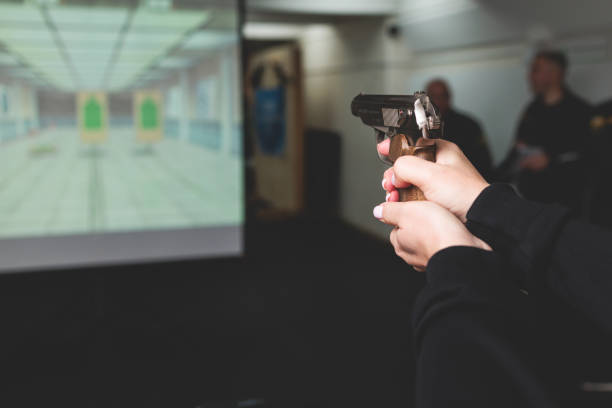 istock Process of shooting target at the shooting rifle range, women practicing with hand gun pistol at shooting gallery, firearms training, pointing weapon on digital screen, live fire digital targeting 1805737737