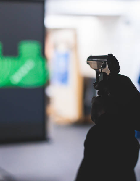 istock Process of shooting target at the shooting rifle range, women practicing with hand gun pistol at shooting gallery, firearms training, pointing weapon on digital screen, live fire digital targeting 1805737738