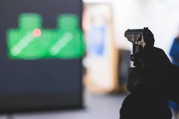istock Process of shooting target at the shooting rifle range, women practicing with hand gun pistol at shooting gallery, firearms training, pointing weapon on digital screen, live fire digital targeting 1805737764