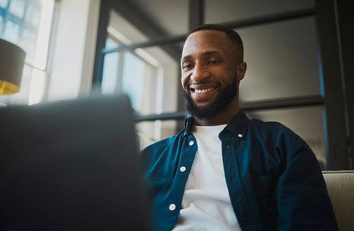 A happy business man typing on a laptop in a modern office setting, showcasing the comfort and efficiency of modern work environments.