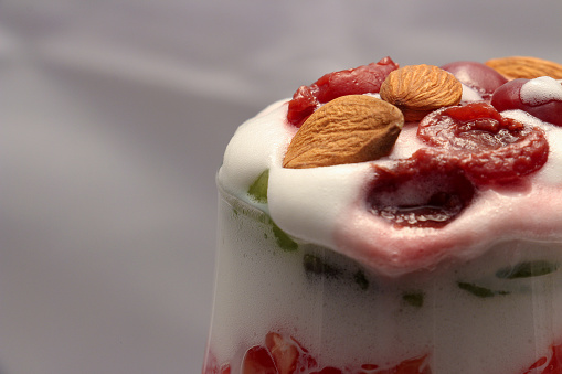 Close up shot of a fruit salad with cream served in a glass.