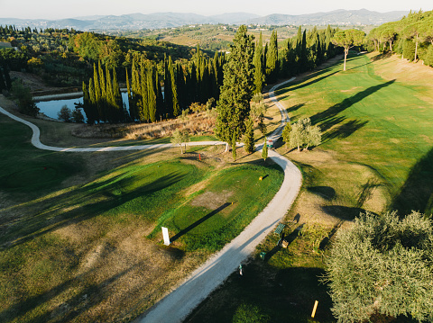 Aerial view of a golf course at sunset. Drone point of view of a golf course with greens and sand traps.