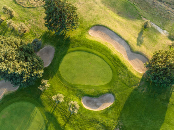 Aerial view of a golf course at sunset. Drone point of view of a golf course with greens and sand traps.