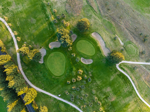 Aerial view of a golf course at sunset. Drone point of view of a golf course with greens and sand traps.