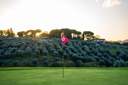 A golf green at sunset with flag. No people and copy space.