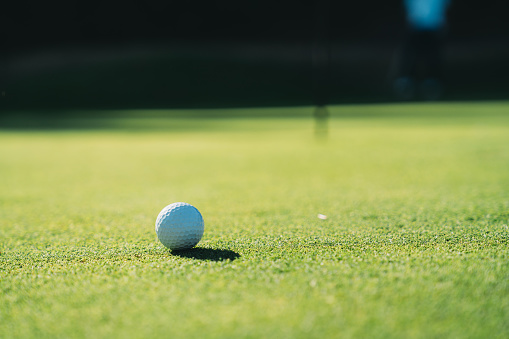 Selective focus on a golf ball on green. No people and room for copy space.