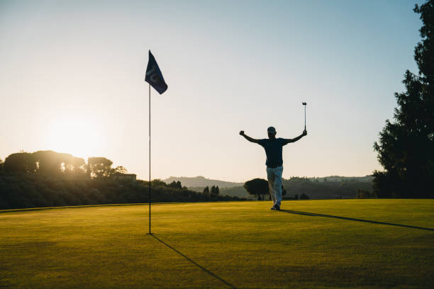 istock A golfer is celebrating a hole at sunset on the green 1805750991